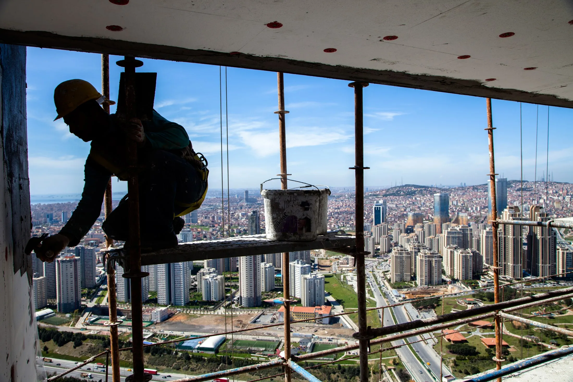 A worker on scaffolding high above the city, with the NEXO colour treatment