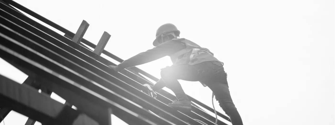 A worker assembling the structure of a building against the light, with the NEXO colour treatment
