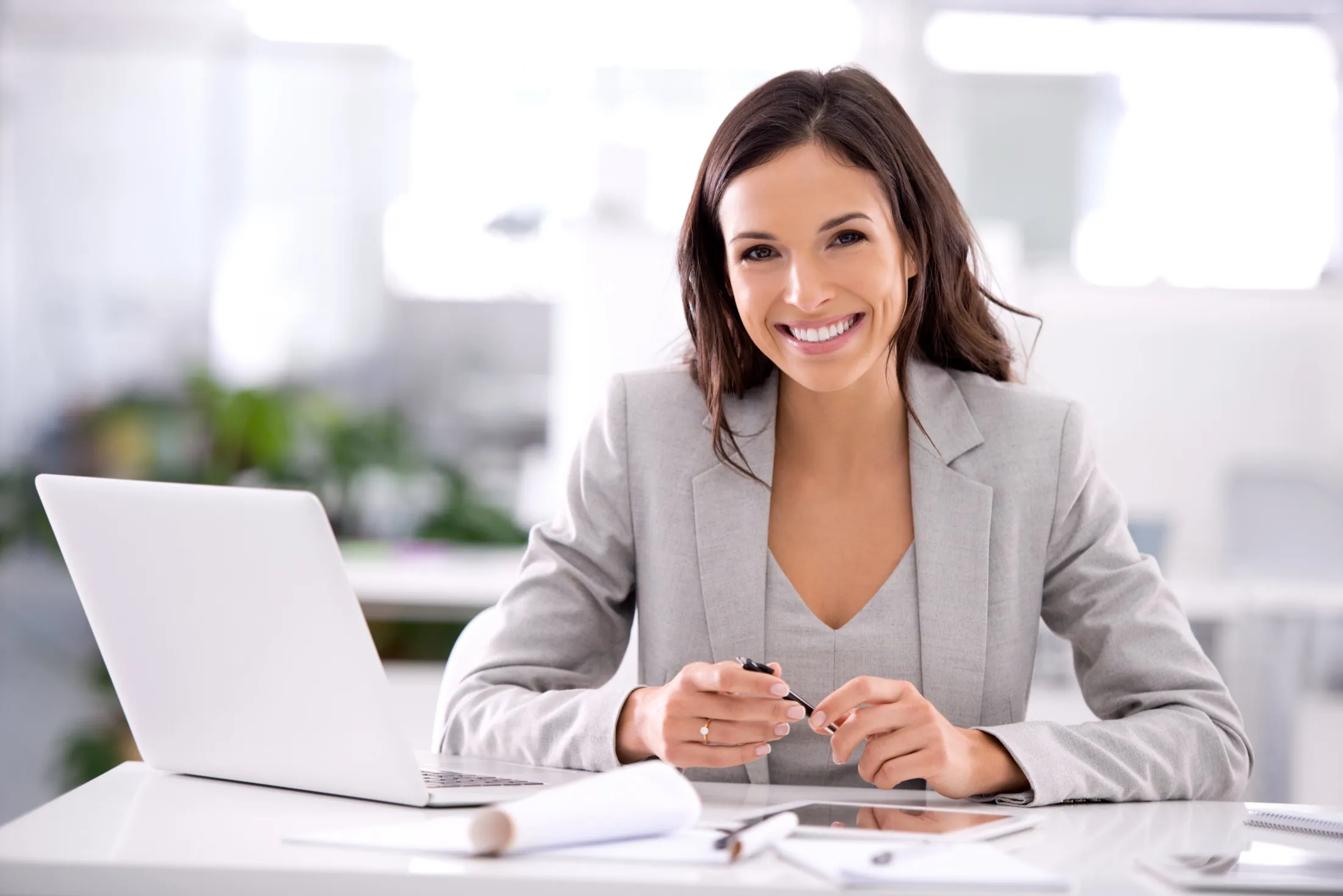 A smiling executive at her desk in a bright office, with the NEXO colour treatment