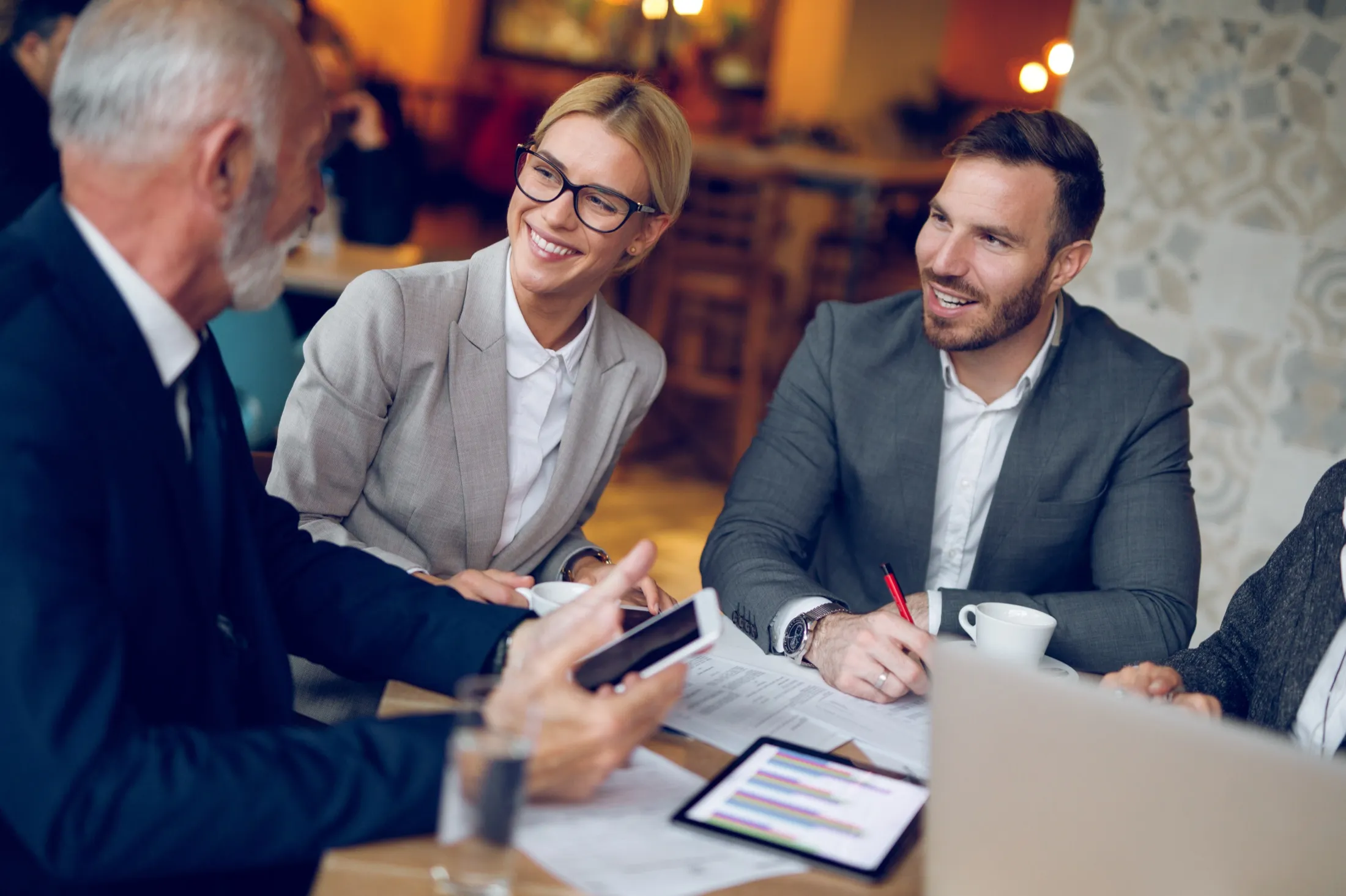 Tres profesionales conversando alrededor de una mesa de trabajo con documentos, con el tratamiento de color de NEXO