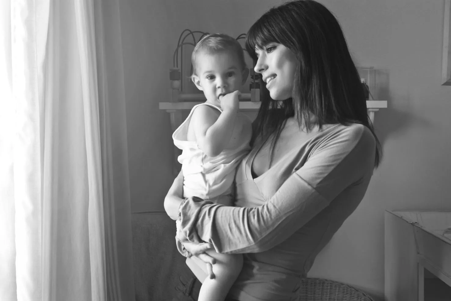 A mother holding her baby by a window, with the NEXO colour treatment