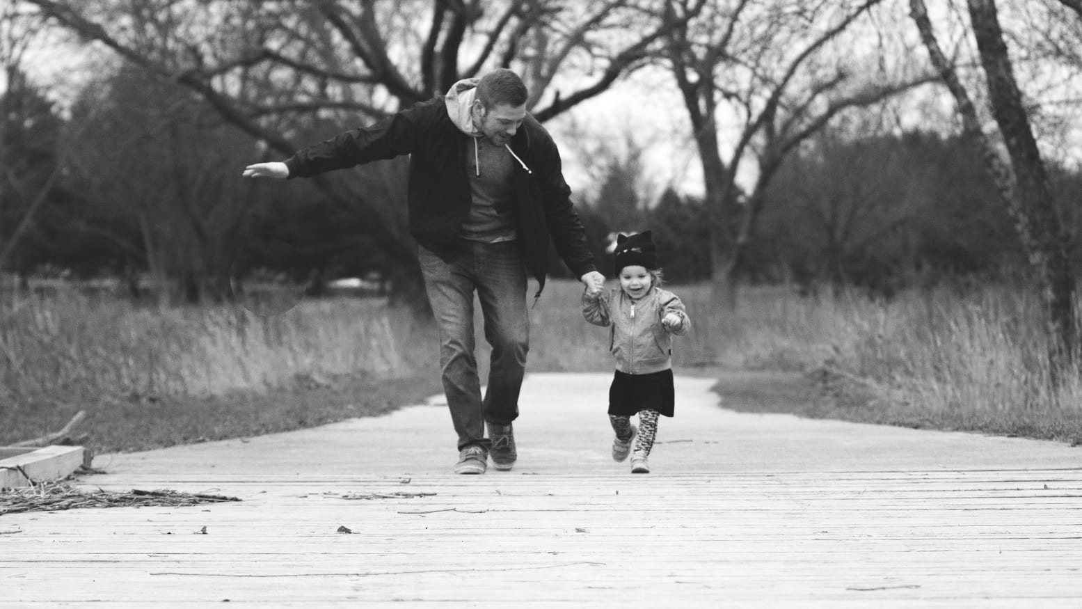 Un padre y su hija caminando de la mano por un parque, con el tratamiento de color de NEXO